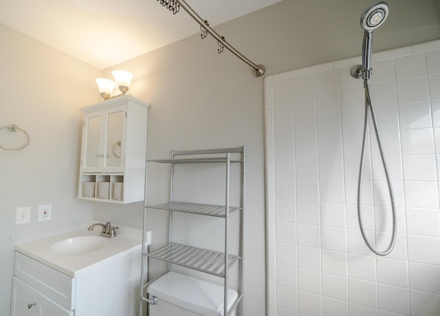 bathroom featuring tiled shower, vanity, and toilet