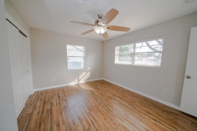 spare room featuring ceiling fan, light hardwood / wood-style floors, and a healthy amount of sunlight