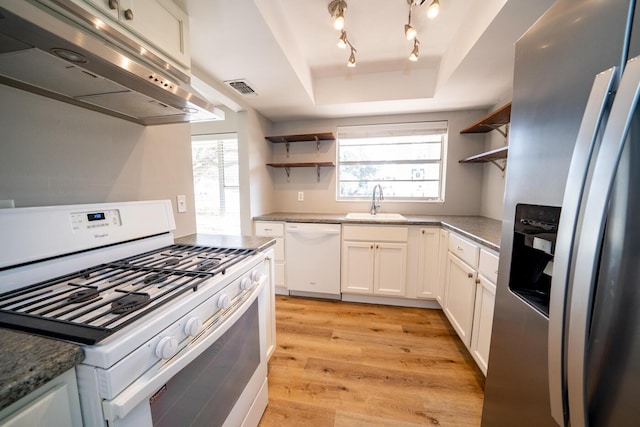 kitchen with extractor fan, white cabinetry, a tray ceiling, plenty of natural light, and white appliances