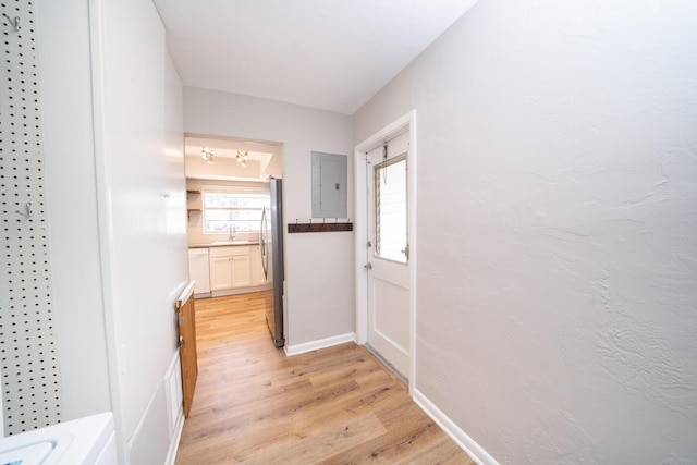 corridor with sink, electric panel, and light hardwood / wood-style floors