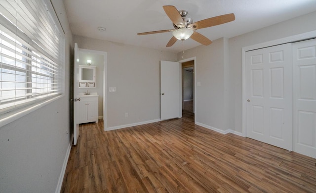 unfurnished bedroom featuring dark hardwood / wood-style floors, sink, ceiling fan, and a closet