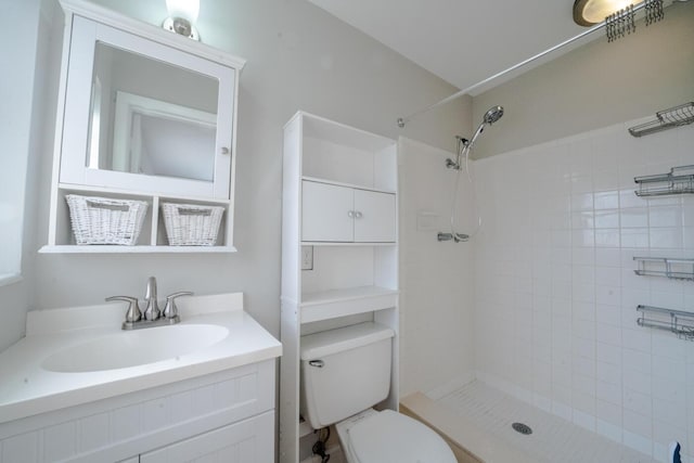 bathroom with vanity, a tile shower, and toilet