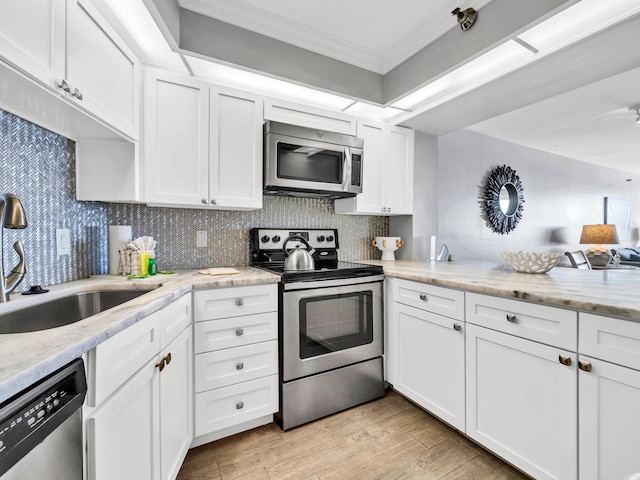 kitchen featuring white cabinetry, sink, backsplash, light hardwood / wood-style floors, and appliances with stainless steel finishes