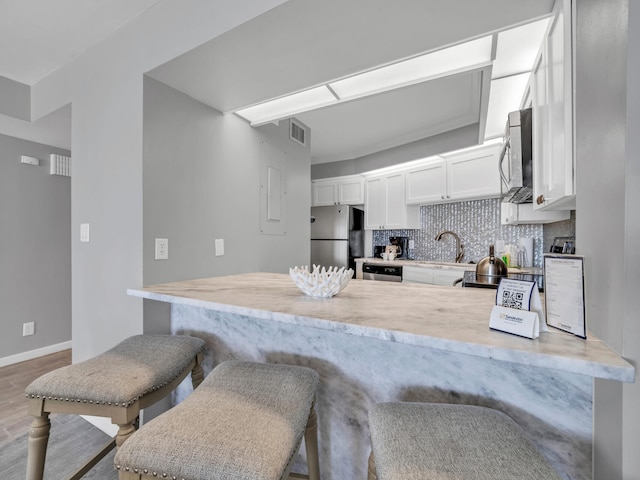 kitchen featuring white cabinets, kitchen peninsula, a breakfast bar area, and appliances with stainless steel finishes