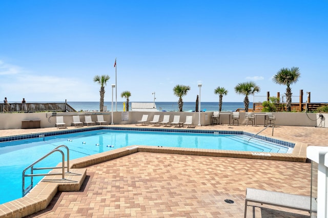 view of pool featuring a patio and a water view