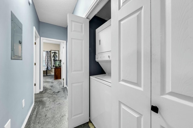 washroom featuring stacked washer / drying machine, light colored carpet, a textured ceiling, and electric panel