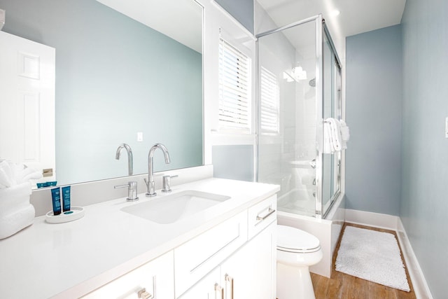 full bathroom featuring hardwood / wood-style floors, vanity, toilet, and enclosed tub / shower combo