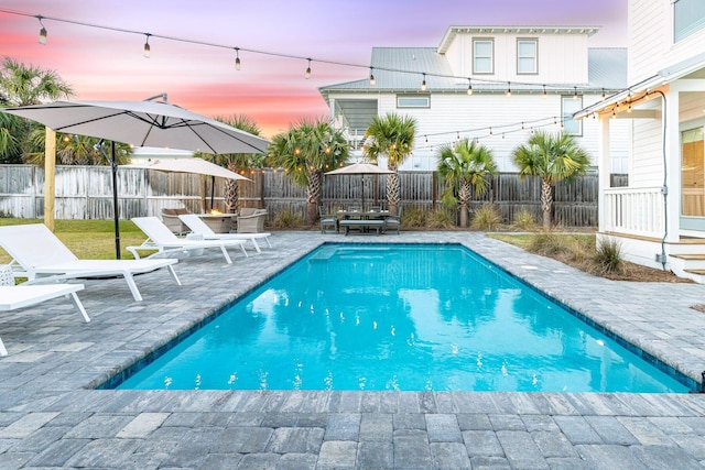 pool at dusk featuring a patio