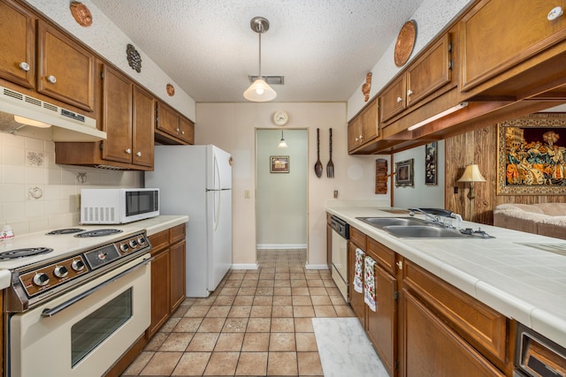 kitchen featuring sink, tile countertops, hanging light fixtures, white appliances, and backsplash