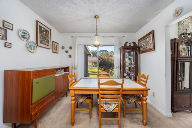 dining area with a chandelier, light carpet, and a textured ceiling