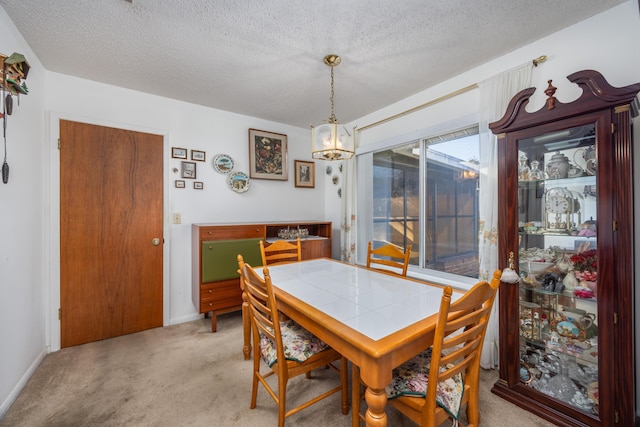 carpeted dining room featuring a notable chandelier and a textured ceiling