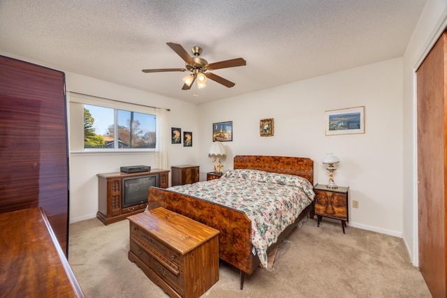 bedroom featuring light colored carpet, a textured ceiling, ceiling fan, and a closet