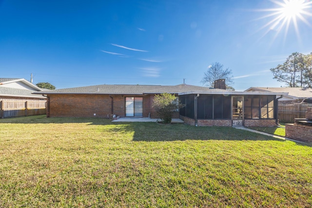 back of property featuring a sunroom and a lawn