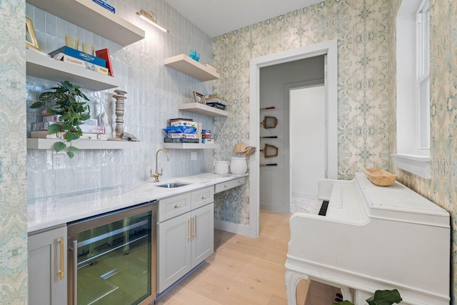 bar featuring sink, beverage cooler, tasteful backsplash, light hardwood / wood-style flooring, and gray cabinets