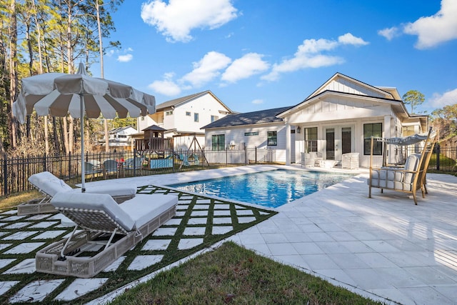 view of pool with a patio area, a playground, and french doors