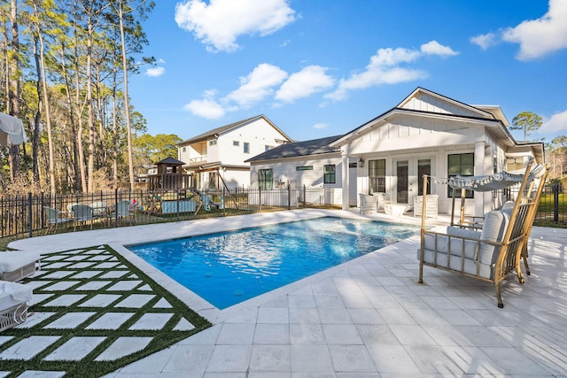 view of swimming pool with a patio area, a playground, and french doors