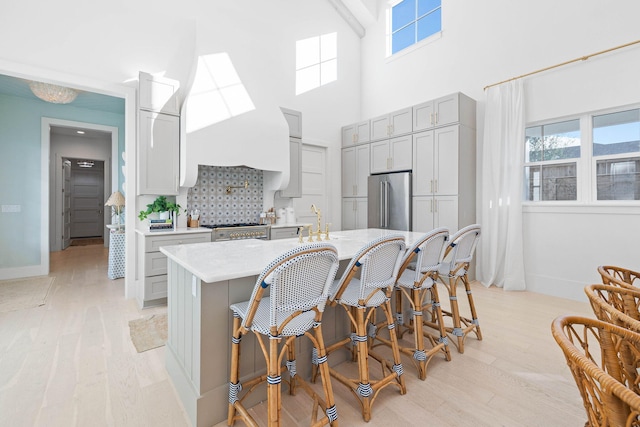 kitchen featuring gray cabinetry, a kitchen bar, appliances with stainless steel finishes, and light hardwood / wood-style flooring