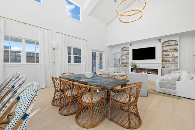 dining space featuring light hardwood / wood-style floors, built in features, a high ceiling, and a chandelier