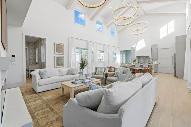 living room with beam ceiling, light wood-type flooring, a towering ceiling, and a chandelier