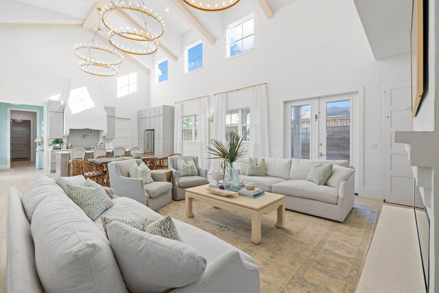 living room featuring a high ceiling, french doors, light wood-type flooring, beamed ceiling, and a notable chandelier