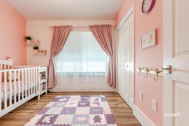 bedroom with light hardwood / wood-style flooring, a nursery area, and a closet