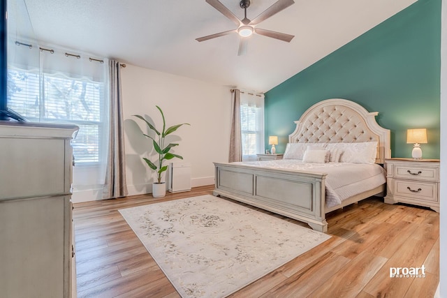 bedroom featuring multiple windows, lofted ceiling, light wood-type flooring, and ceiling fan