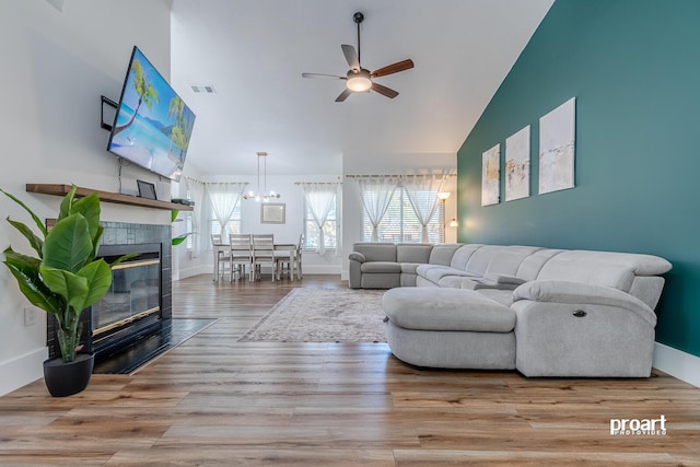 living room with a fireplace, high vaulted ceiling, light wood-type flooring, and ceiling fan