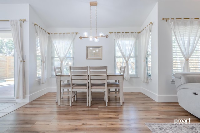 dining space with an inviting chandelier, light hardwood / wood-style flooring, and lofted ceiling