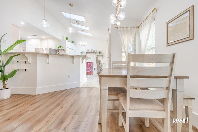 unfurnished dining area featuring lofted ceiling with skylight, a chandelier, and light hardwood / wood-style flooring