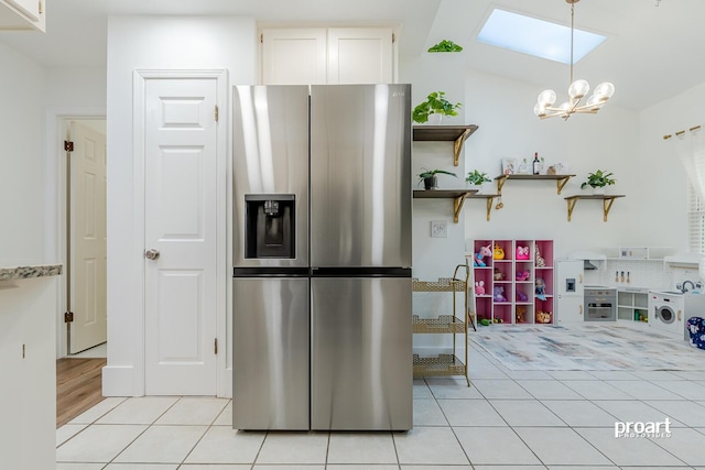 kitchen with lofted ceiling, stainless steel refrigerator with ice dispenser, white cabinets, light tile patterned flooring, and pendant lighting