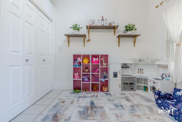 rec room with washer / dryer and light tile patterned floors