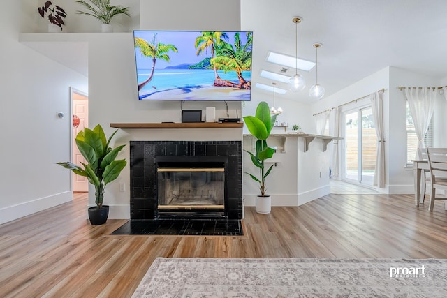 living room featuring a tile fireplace, hardwood / wood-style flooring, and vaulted ceiling