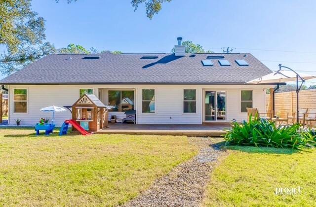 rear view of house with a lawn and a deck