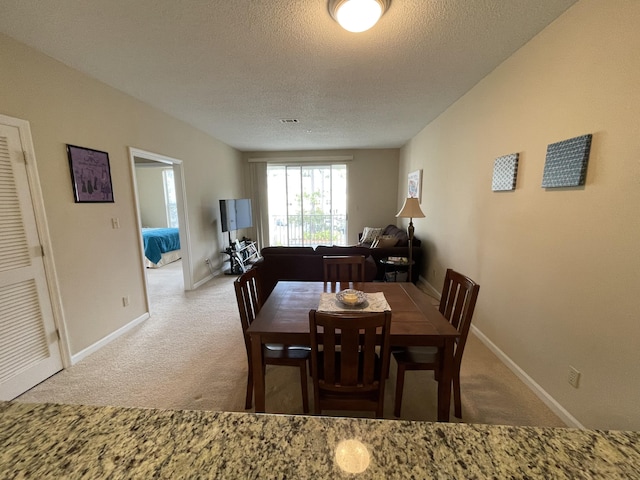 dining area featuring light colored carpet and a textured ceiling