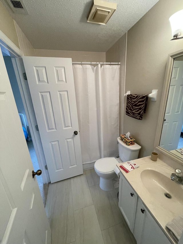 bathroom with vanity, toilet, and a textured ceiling