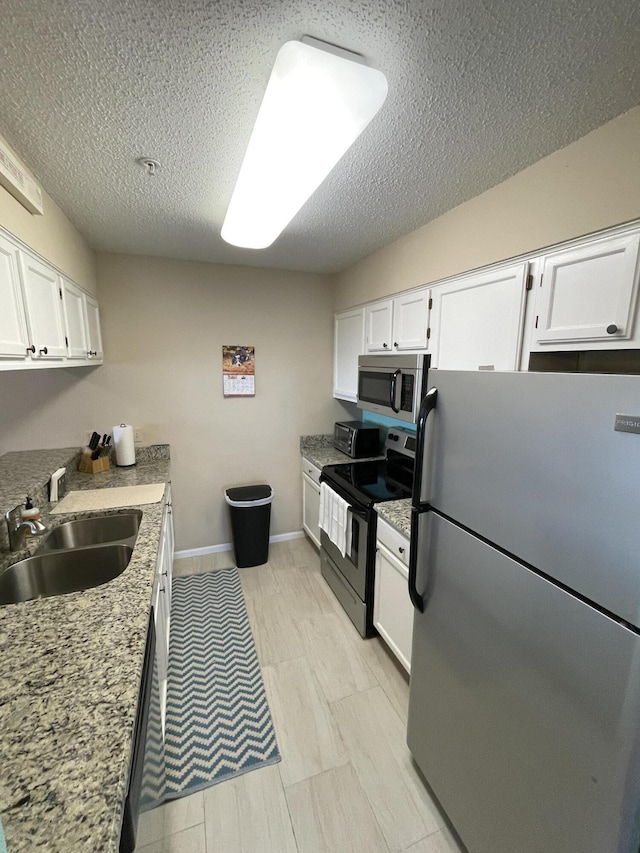 kitchen featuring light stone counters, sink, white cabinets, and appliances with stainless steel finishes