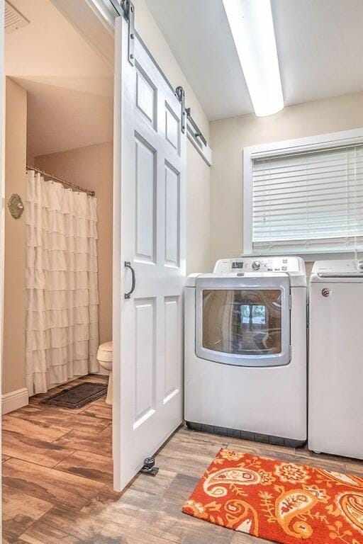 laundry room featuring a barn door, light hardwood / wood-style floors, and washer and clothes dryer