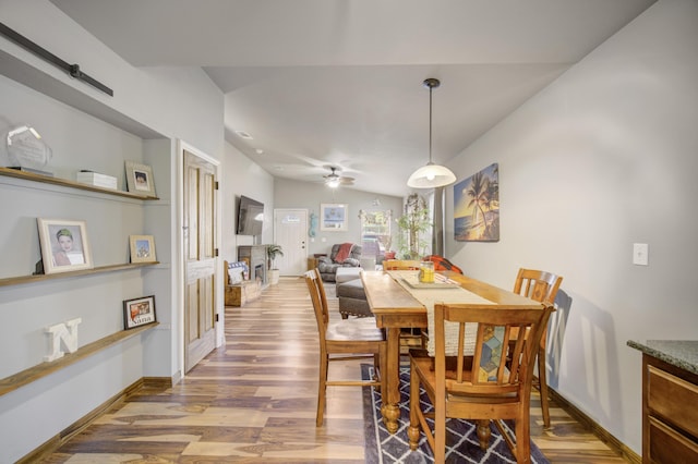 dining space featuring ceiling fan, wood-type flooring, and lofted ceiling