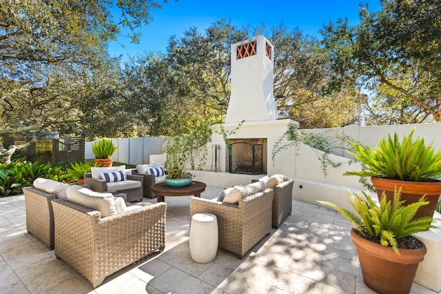 view of patio with an outdoor living space with a fireplace and a fenced backyard