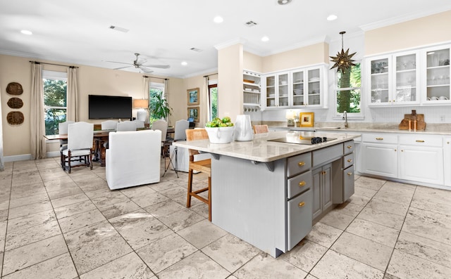 kitchen with black electric stovetop, gray cabinetry, white cabinetry, ornamental molding, and a kitchen bar