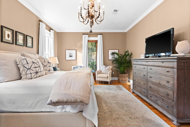 bedroom featuring visible vents, ornamental molding, wood finished floors, a chandelier, and baseboards