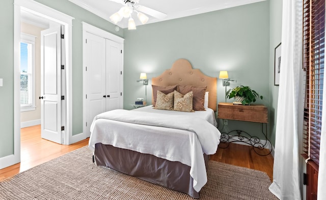 bedroom featuring light wood-style floors, a closet, crown molding, and baseboards