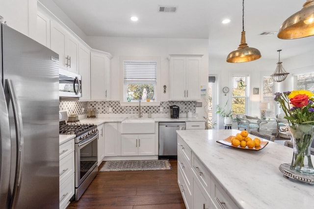 kitchen featuring sink, white cabinetry, hanging light fixtures, and appliances with stainless steel finishes