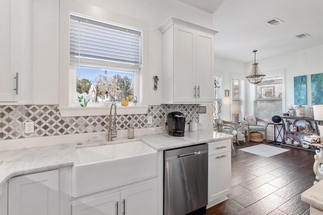 kitchen with stainless steel dishwasher, white cabinets, sink, and light stone countertops