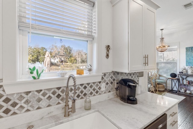 kitchen featuring white cabinetry, a wealth of natural light, and light stone countertops