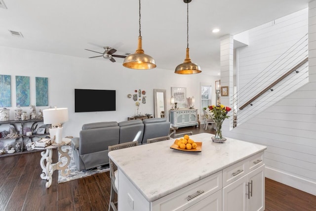 kitchen featuring dark hardwood / wood-style flooring, white cabinets, a center island, and pendant lighting