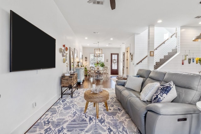 living room with ceiling fan with notable chandelier and hardwood / wood-style flooring