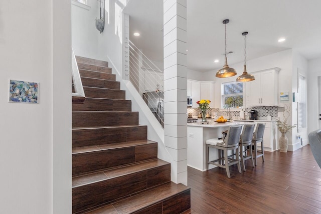 stairway featuring hardwood / wood-style floors and decorative columns