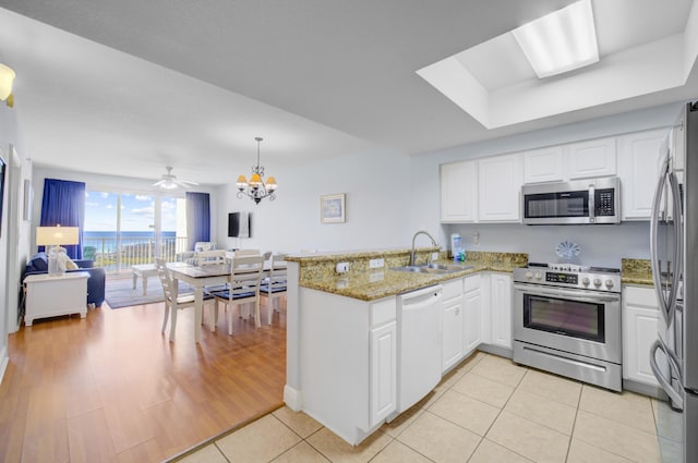 kitchen with white cabinets, sink, light tile patterned flooring, kitchen peninsula, and stainless steel appliances