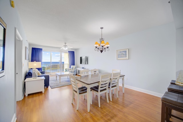 dining area with light hardwood / wood-style flooring and ceiling fan with notable chandelier